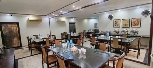 a restaurant with tables and chairs in a room at Herfa INN Hotel Lahore in Lahore