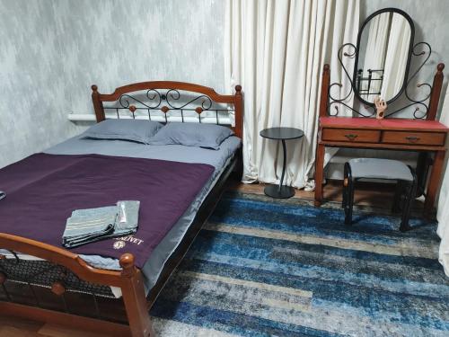 a bedroom with a bed and a table and a mirror at Guest house Gosling in Almaty