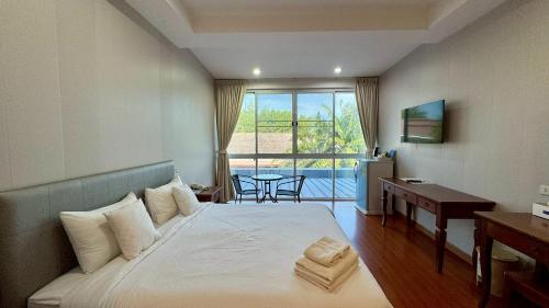 a bedroom with a bed and a desk and a window at Baan Suan Khun Ta and Golf Resort in Ubon Ratchathani