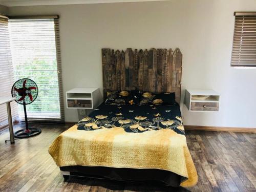 a bedroom with a bed with a wooden headboard at Twin Power Guesthouse in Bloemfontein