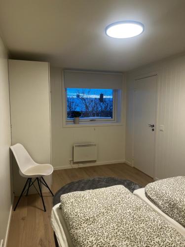 a bedroom with two beds and a chair and a window at Nyoppusset leilighet i Vadsø in Vadsø