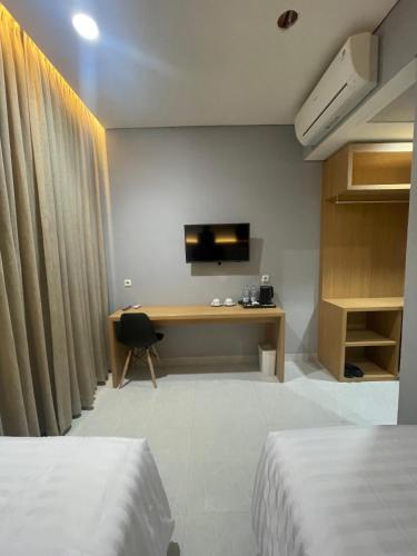 a bedroom with two beds and a desk with a television at Agiva Hotel in Kurinci