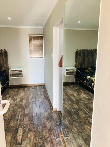 an empty room with a bed and a mirror at Twin Power Guesthouse in Bloemfontein