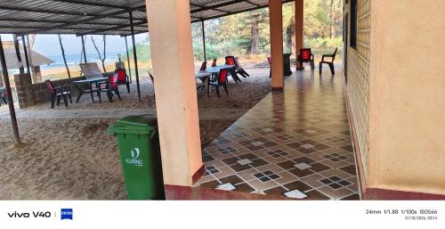 a trash can sitting outside of a building with tables and chairs at Silver sand beach resort in Malvan