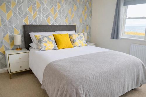 a bedroom with a bed with yellow and blue pillows at Sunset House On The Beach in Maryport