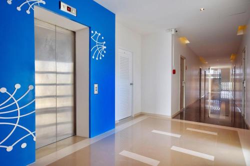 a hallway with a blue wall and a elevator at Aster Canopy Suites & Living in Rayong
