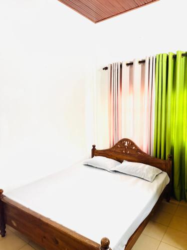 a bed in a room with green and white curtains at S70 Villa in Dickwella