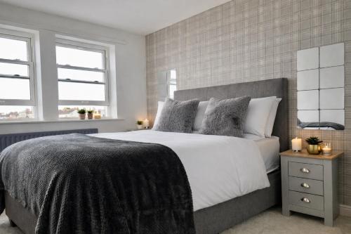 a bedroom with a large bed and two windows at Beautiful Beach Front Cottage in Allonby