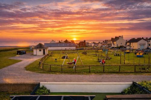 a group of people playing on a playground at sunset at Beautiful Beach Front Cottage in Allonby