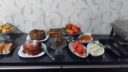 a table topped with different types of food on plates at Hotel Confort Maringá in Maringá