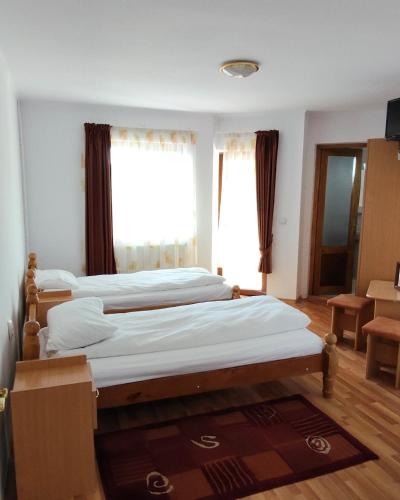 a bedroom with three beds and a window at Pensiunea Patru Brazi in Muntele Cacovei