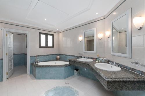 a bathroom with two sinks and two mirrors at Palm Jumeirah - Property Advisers in Dubai