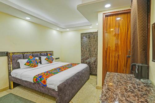a bedroom with a bed and a door to a bathroom at FabHotel Havenora - Nr Maharani Bagh in New Delhi