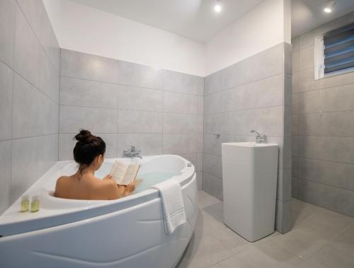 a woman sitting in a bath tub reading a book at Pixel Guesthouse in Târgu Secuiesc