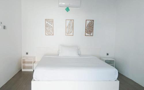 a white bed in a room with three pictures on the wall at La Plage Beach Club in Tjikakaka