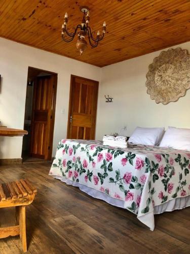 a bedroom with a bed with a floral bedspread at Pousada Joaninha in Tiradentes