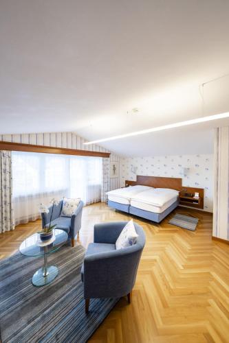 a bedroom with a bed and a couch and a chair at Hotel Hecht in Appenzell