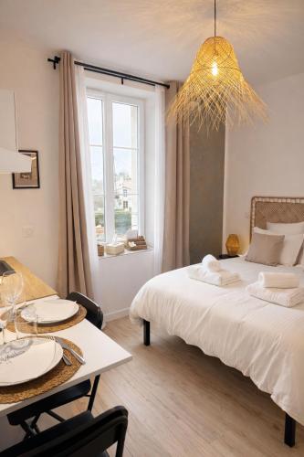 a bedroom with a bed and a table and a window at La Villa Blanche Appart hôtel in Salles