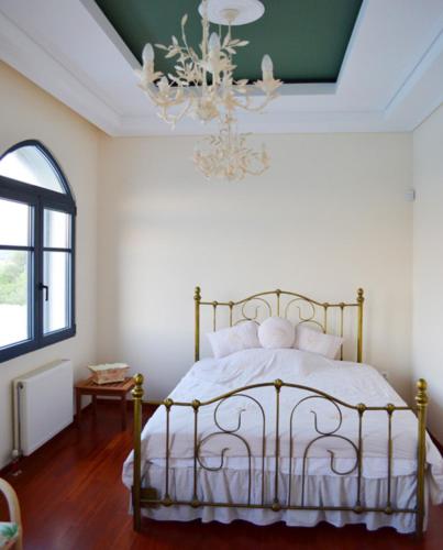 a bedroom with a bed with a chandelier at Mikamas Villas in Pyrgi Thermis