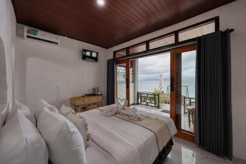 a bedroom with a bed with a view of the ocean at Road Beach Cottages in Nusa Penida
