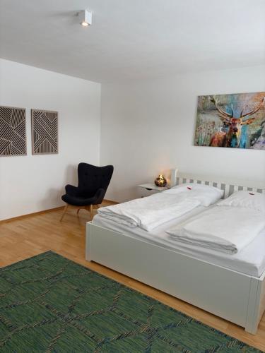 a bedroom with a white bed and a black chair at Ferienwohnung Madera Campesina in Hunderdorf