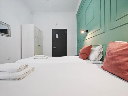 a bedroom with two beds with white sheets and red pillows at Cosy room 6 in Tal-Pietà
