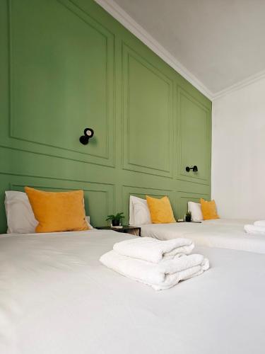 two beds in a green room with towels on them at Cosy room 5 in Tal-Pietà