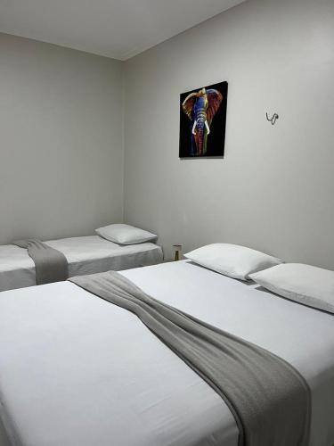 a room with three beds and a picture on the wall at Stillo Açaí Hospedaria in Bragança