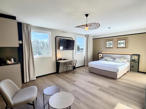 a hotel room with a bed and a desk and chairs at Brit Hotel Saint-Méen-le-Grand en Brocéliande in Saint-Onen-la-Chapelle