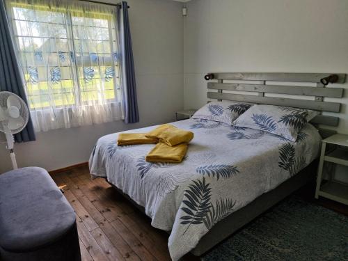 a bedroom with a bed with two yellow towels on it at Elmscote Cottages - Cabin 2 in Krugersdorp