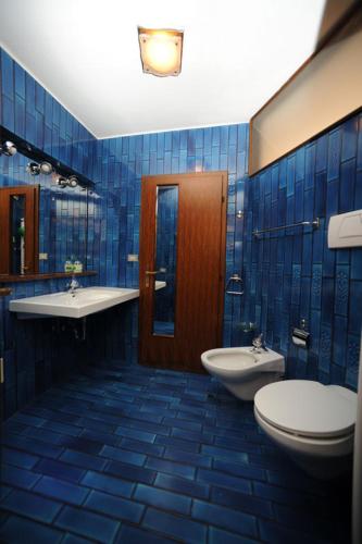 a blue tiled bathroom with two toilets and a sink at Appartamento IN CENTRO a Predazzo in Predazzo