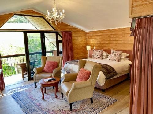 a bedroom with a bed and two chairs and a chandelier at Heuwelsig Farm Cottages in Franschhoek
