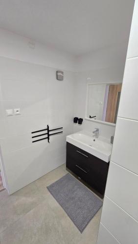 a white bathroom with a sink and a mirror at Dom Hlohovec Center in Hlohovec