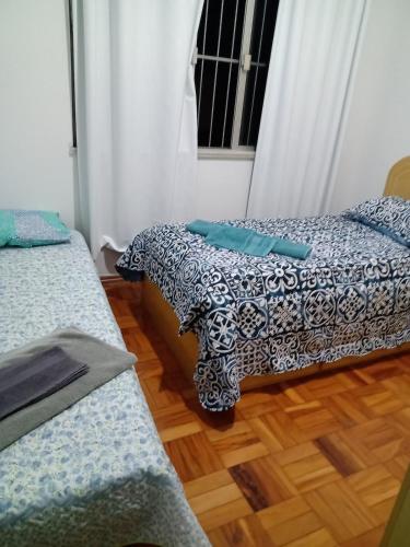 two beds in a room with a wooden floor at Tranquility with convenience in Caxambú Tranquilo in Caxambu