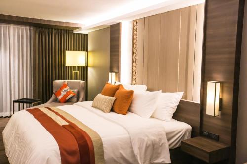 a bedroom with a large white bed with orange pillows at Arte Hotel - SHA Extra Plus in Bangkok