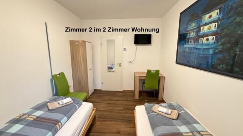 a room with two beds and a tv on the wall at Kim Ferienwohnung B in Sömmerda