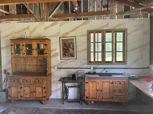 a kitchen with wooden cabinets and a sink and a window at Camping Fazenda Serramar in Palhoça