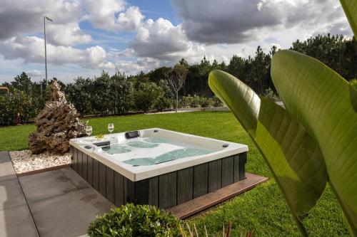 a jacuzzi tub in a yard with plants at Lagoon Residence 56 Deluxe in Óbidos