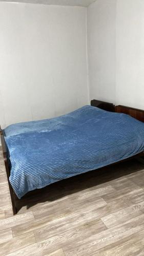 a bedroom with a bed with a blue blanket on it at Old Guesthouse Tsikhisdziri in Tsikhisdziri