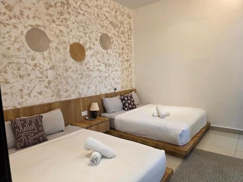 a room with two beds and a wall at One Summerday in Desaru in Kangkar Chemaran