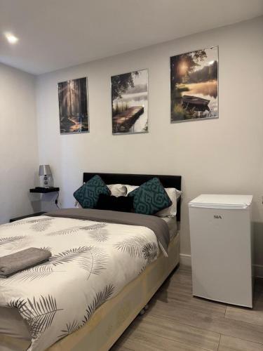 a bedroom with a bed and some pictures on the wall at The Brigstock Nest in Thornton Heath