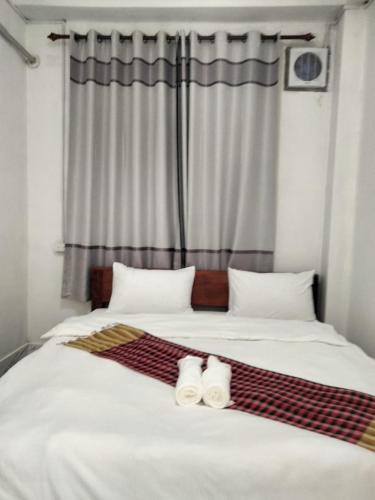 a bedroom with a large bed with two towels on it at Khamfong Guesthouse in Pakbeng