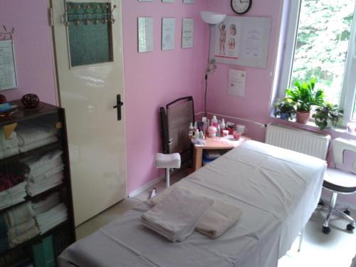 a hospital room with a bed and a table and a clock at Penzion Valovi in Merklín