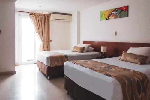 a hotel room with two beds and a window at Hotel Bachue in Barrancabermeja