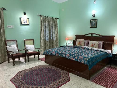 a bedroom with a large bed and two chairs at Udai Niwas - Bikaner in Bikaner