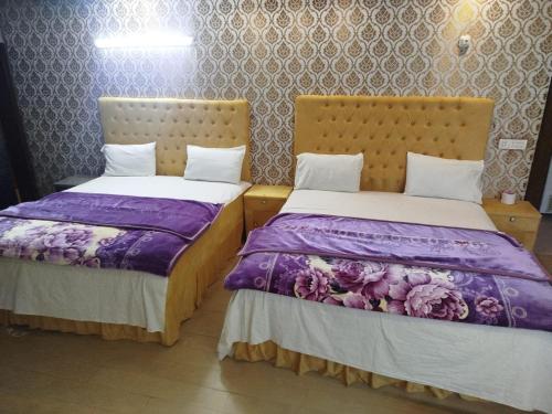 two beds sitting next to each other in a room at Grand Orchard One Hotel in Lahore