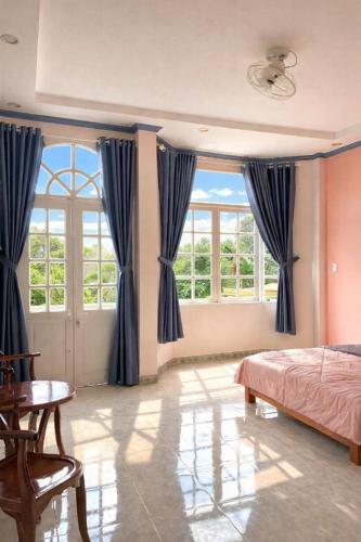 a bedroom with blue curtains and a bed and a table at PINK Hotel Cần Thơ in Can Tho
