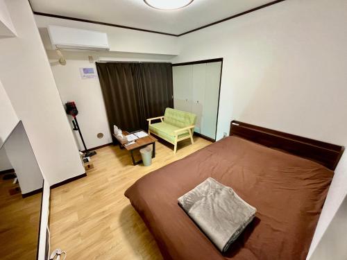 a bedroom with a bed and a green chair at Stay Plus Sophia in Utsunomiya