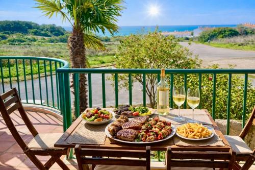 a table with two plates of food and two glasses of wine at Casa Da luz 5 - sea view 2 bedrooms apt , beach & swimming-pool in Luz