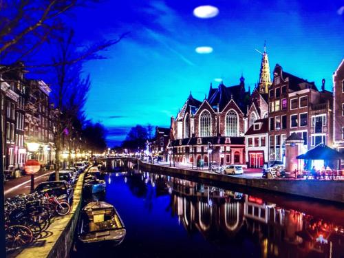 a river with buildings and boats in a city at night at Hotel Anco in Ons Belang